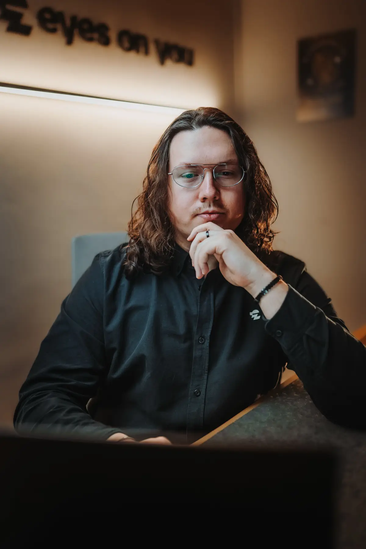 Kenan Adam, Marketing- und Webdesigner, nachdenklich mit der Hand am Kinn in seinem Studio