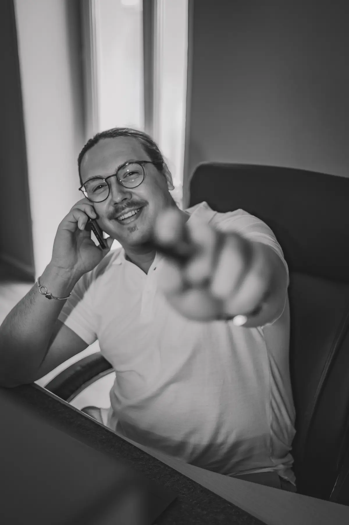 Kenan Adam am Telefon zeigt auf die Kamera, schwarzweiß