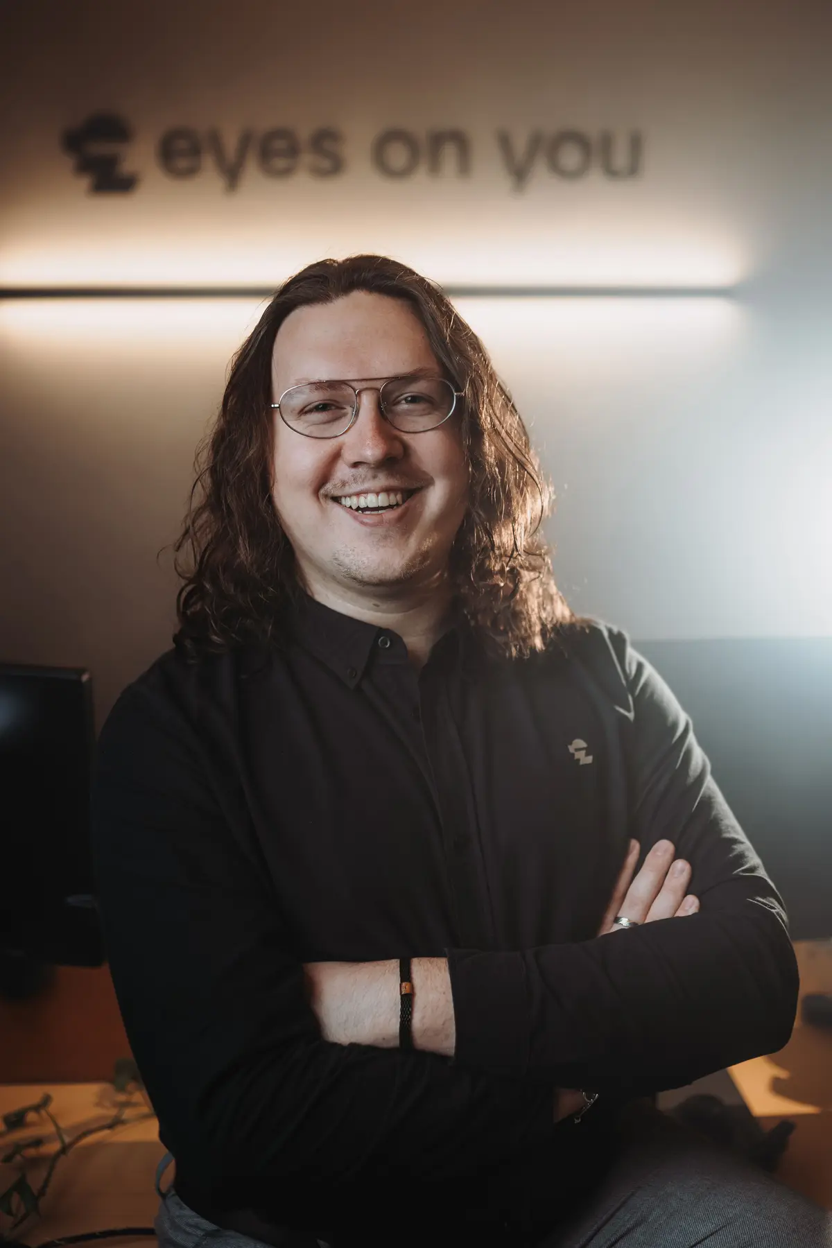 Kenan Adam, Web- und Brand-Designer aus der Oberpfalz, lächelt mit verschränkten Armen in seinem Studio