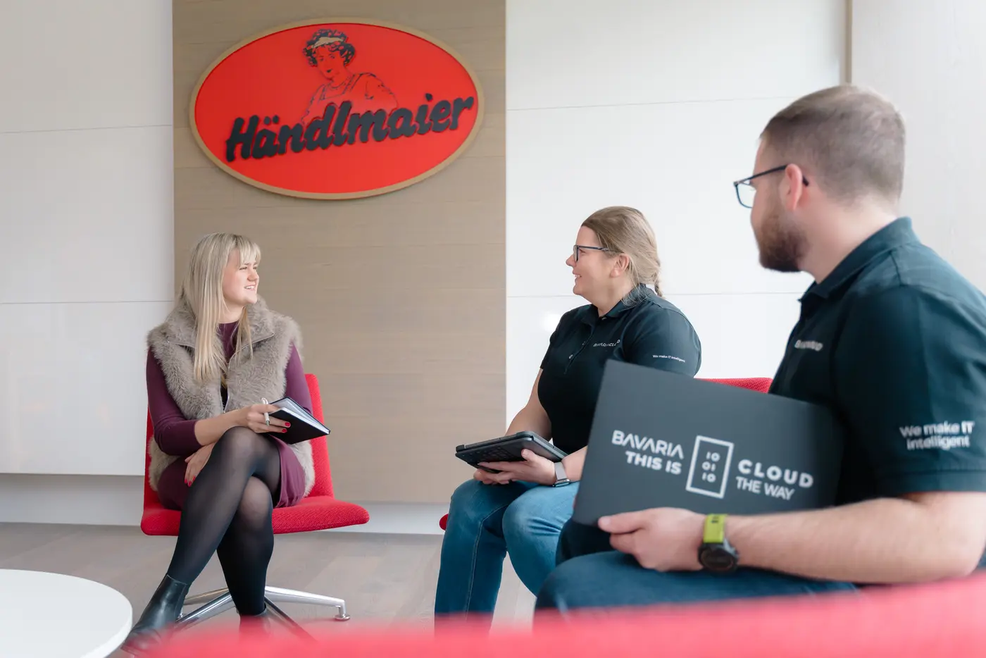BavariaCloud-Mitarbeiter mit gebrandetem Notizbuch im Gespräch bei Händlmaier