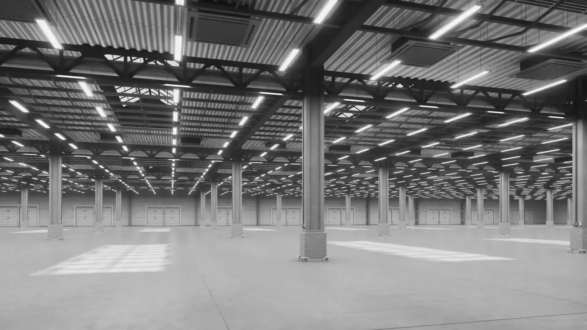 Leere Industriehalle mit langen Lichtreihen an der Decke, schwarzweiß
