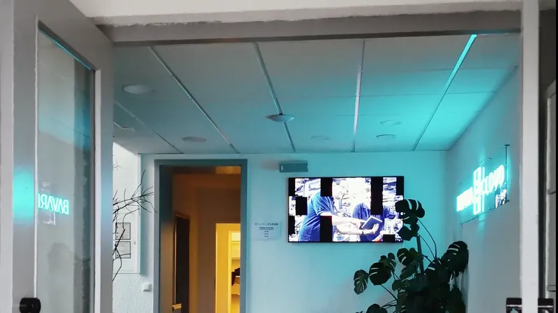 Standbild aus einem Imagefilm: Büroflur mit türkisem Licht und einem Bildschirm an der Wand