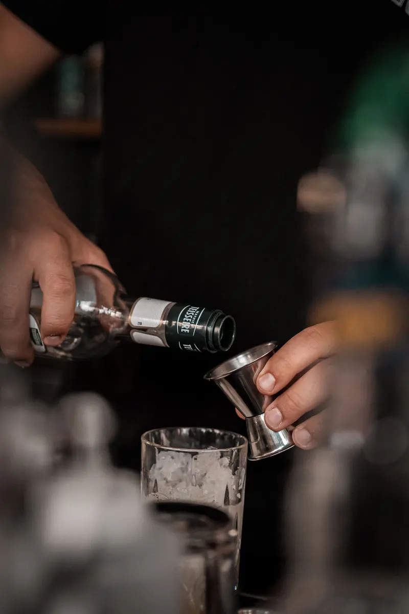 Barkeeper gießt einen Drink aus der Flasche in einen Messbecher