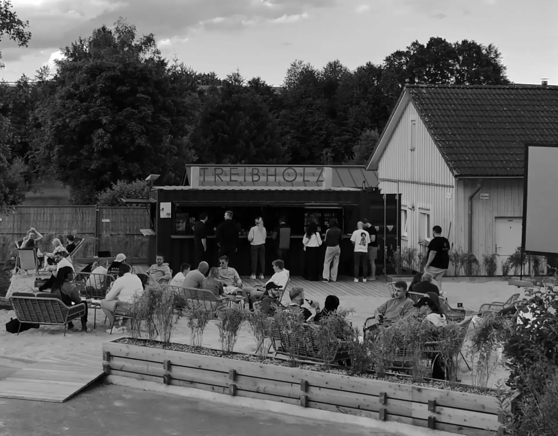 Die Treibholz Beachbar am Naturbadesee mit Gästen auf der Terrasse, schwarzweiß