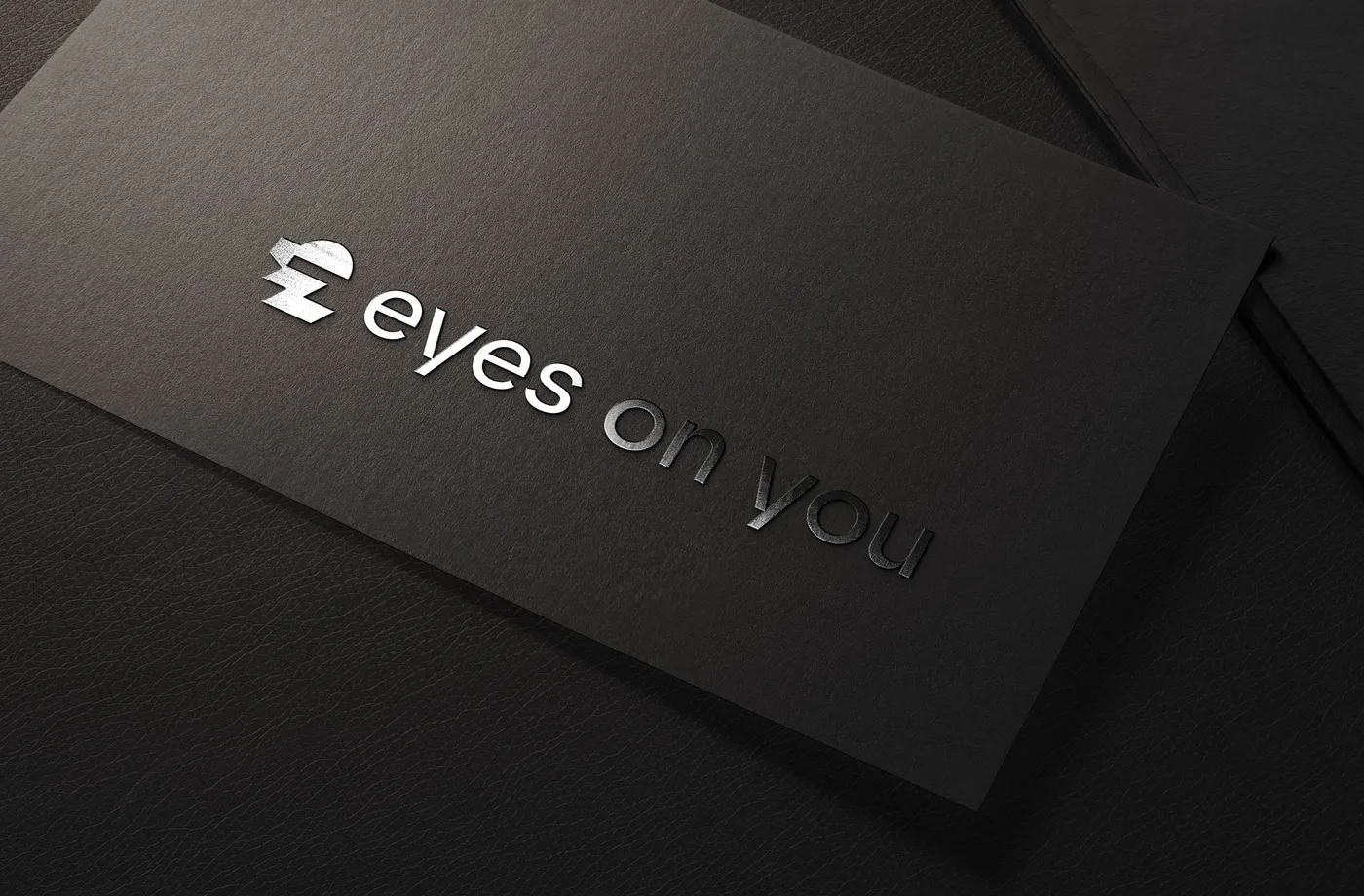 Schwarze Karte mit geprägtem eyes-on-you-Logo, Nahaufnahme der Veredelung